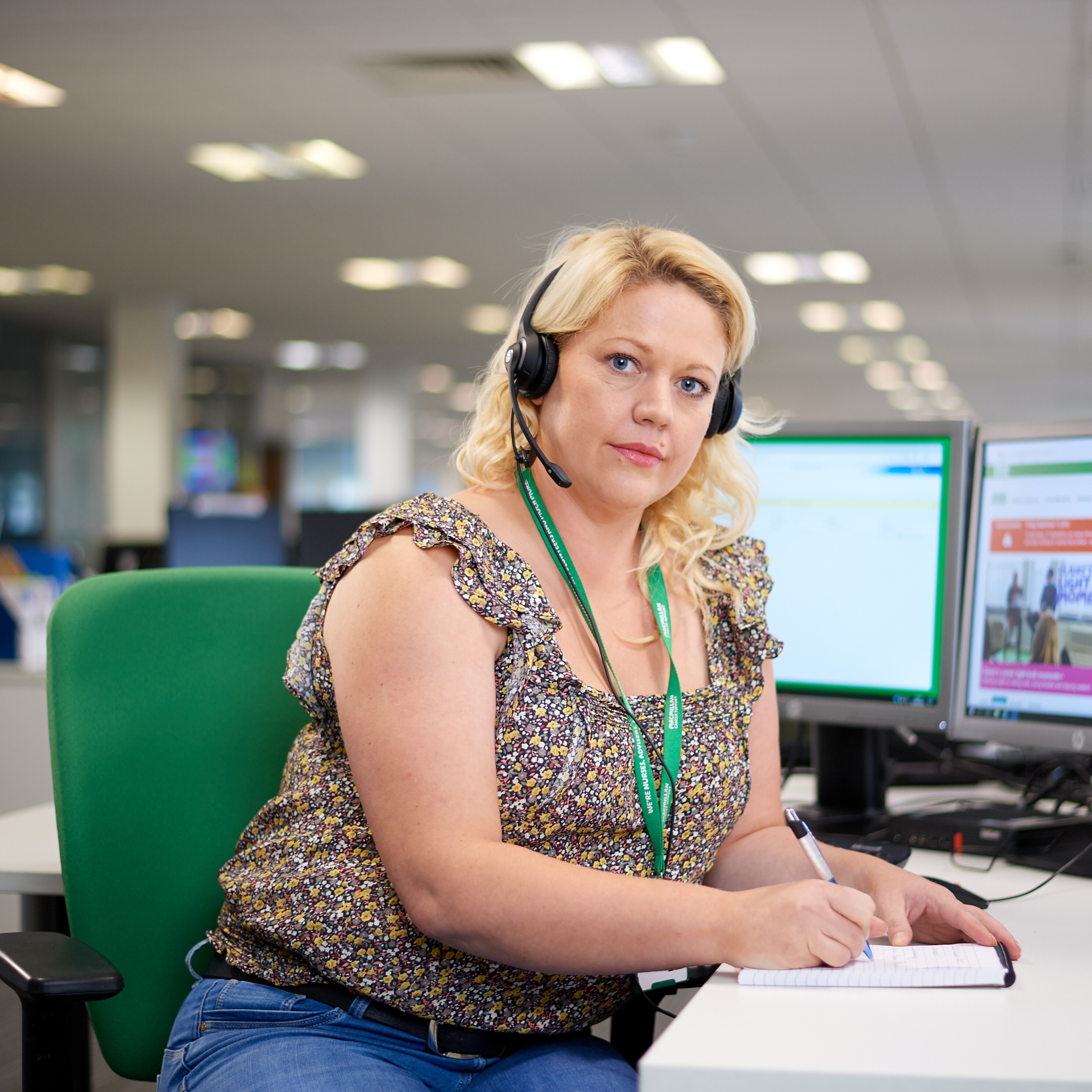 An MSL welfare rights adviser. She wears a telephone headset and holds a pad of paper and a pen.
