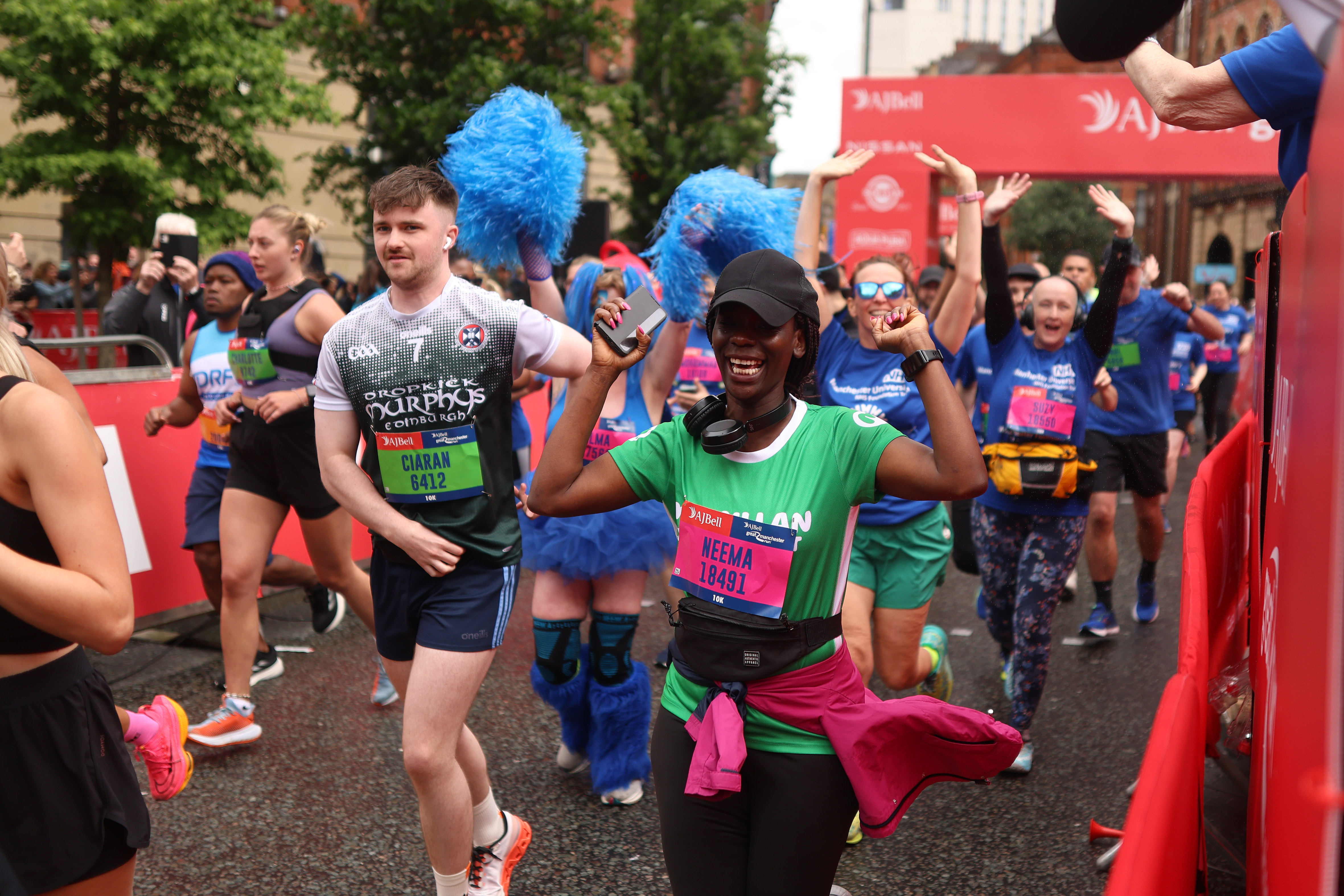 Neema running for Macmillan with a black cap on and green Macmillan running t-shirt