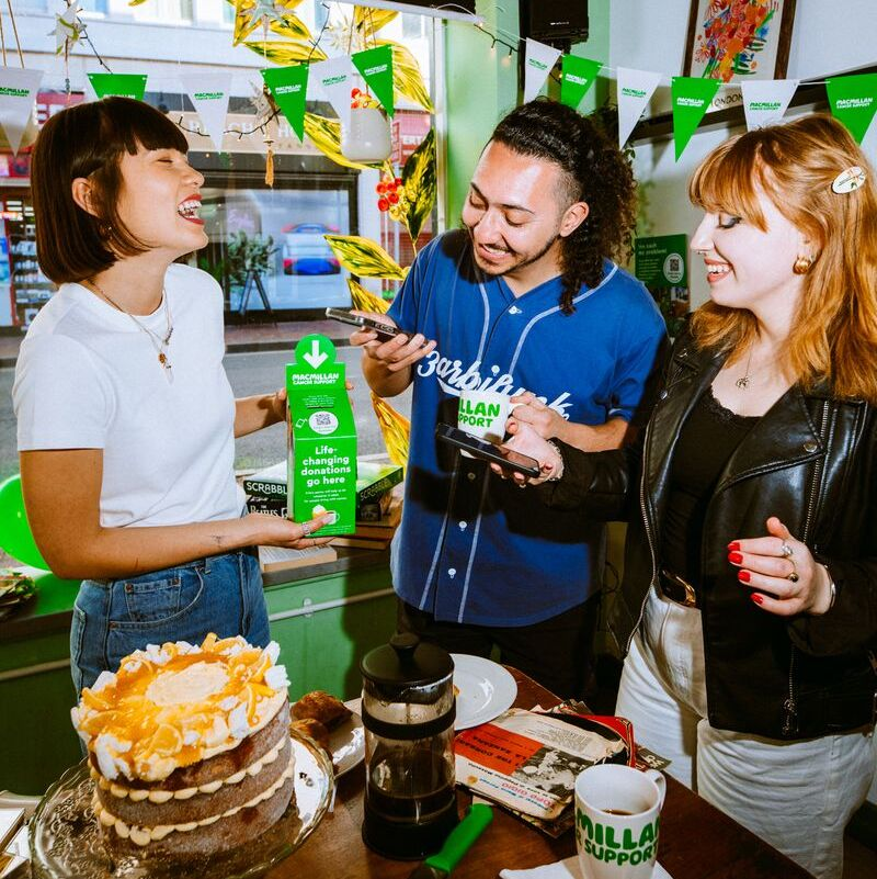 Three people laughing and smiling at a coffee morning