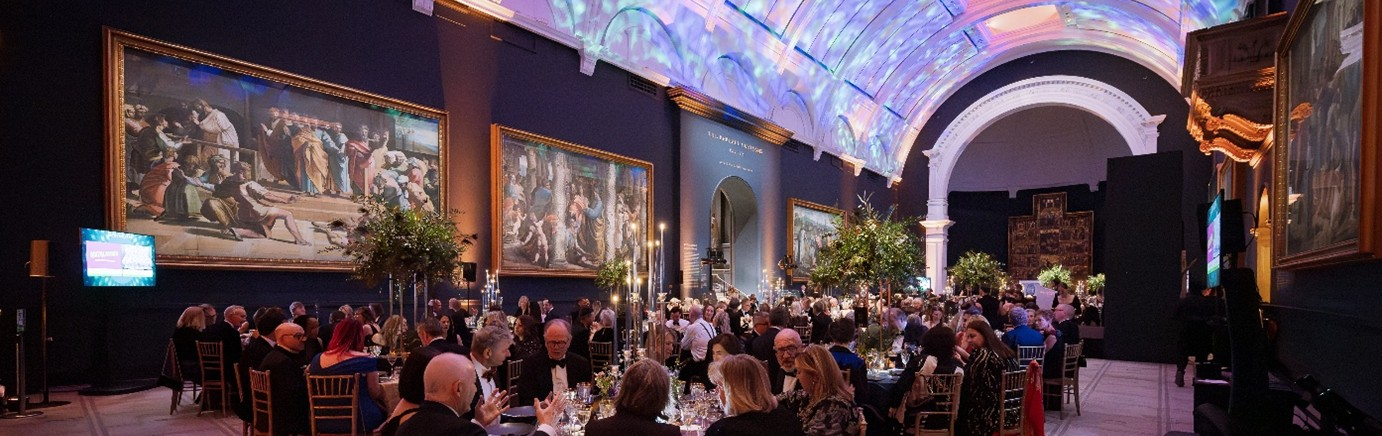 People sat at tables in a grand room at the Macmillan Ball