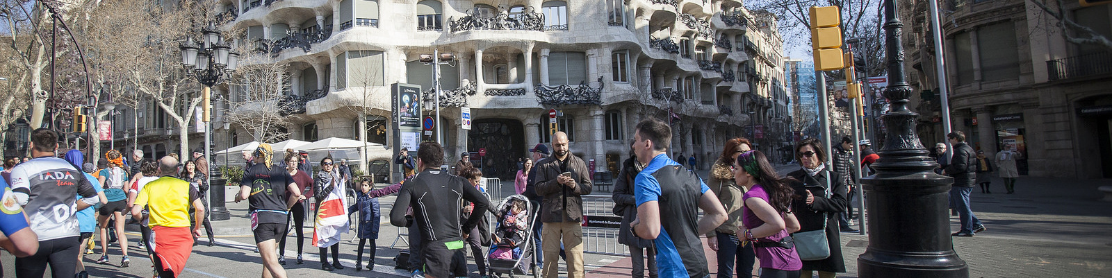 Runners take part in a road race on a city street in Barcelona, passing Casa Milà.