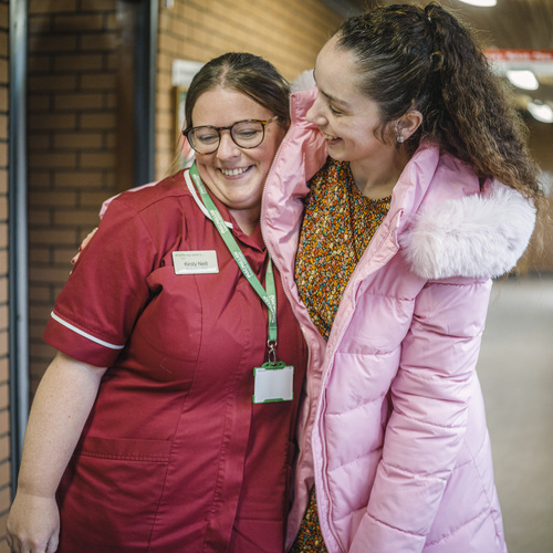 Jess and her Macmillan nurse smiling together in a corridoor.