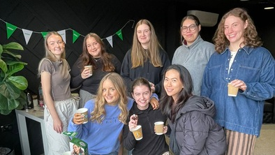 Juliette and the Wholesome Girls Club at their Coffee Morning. They are standing together behind a table full of delicious treats for their event.