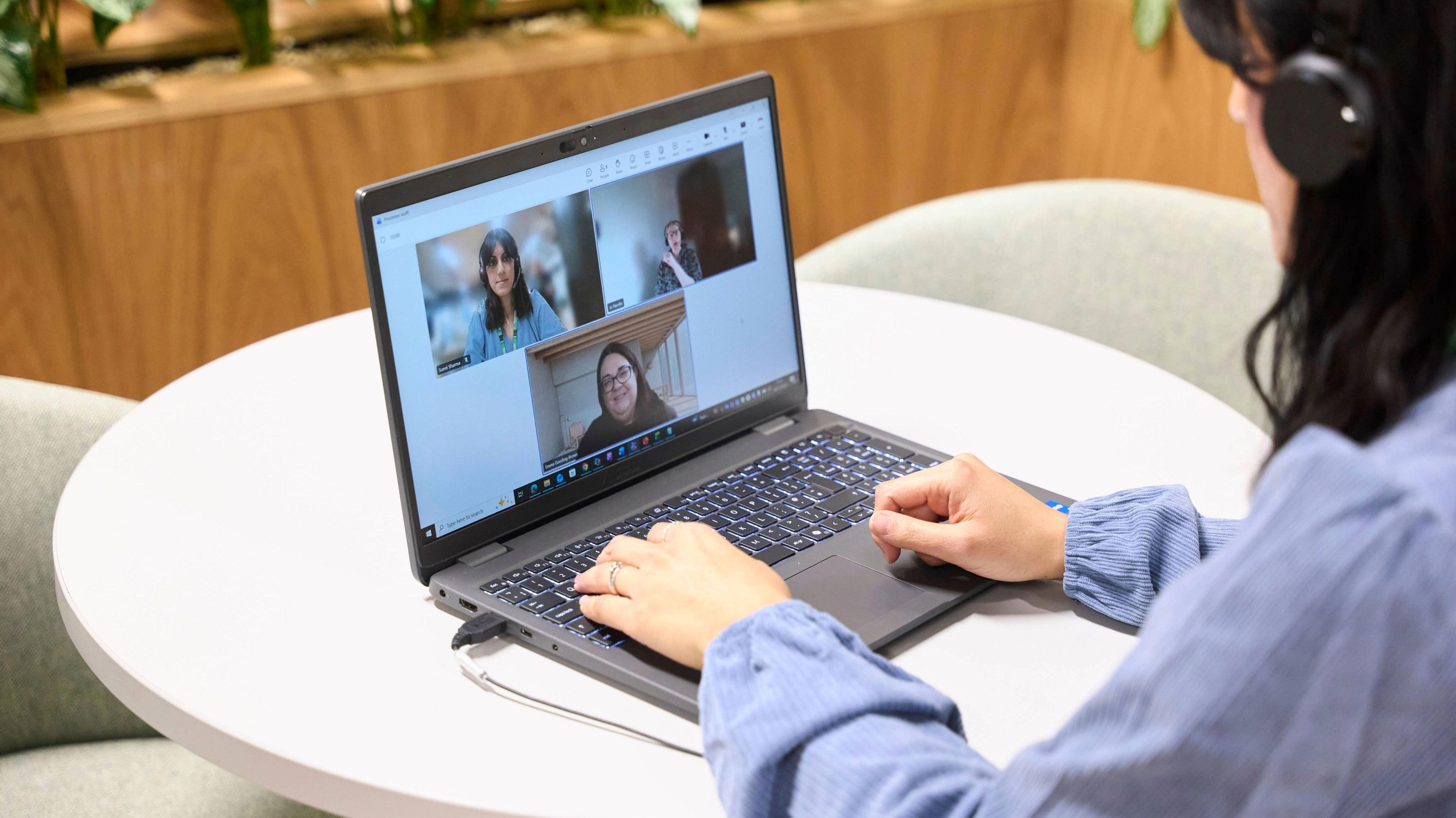 Employee wearing headphones taking part in a video call on a laptop.