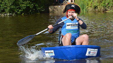 Man wearing a pirate hat paddling a coracle