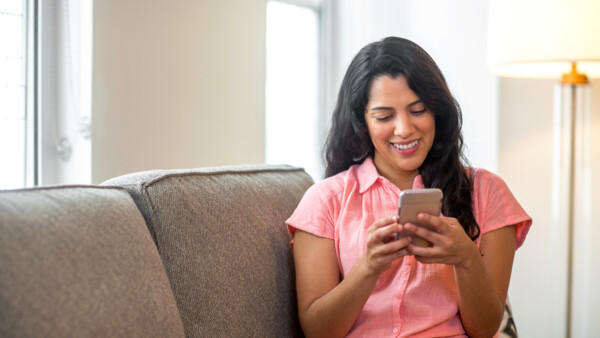 A woman on a sofa looking down at her phone