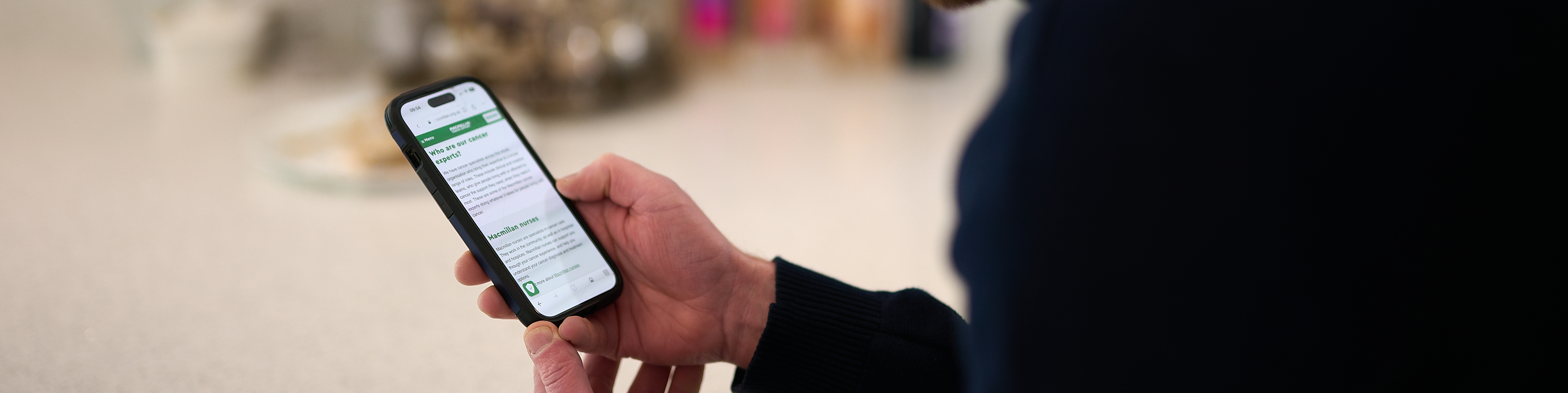 Person reading information on the Macmillan Cancer Support website on a smartphone.