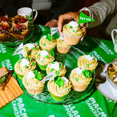 A bundle of yummy vanilla and matcha cupcakes are on top of a clear cake stand. The cupcakes are topped with tasty, rich frosting. 