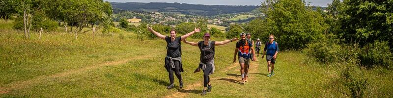 A group of hikers are trekking up a grassy hill in Shropshire.