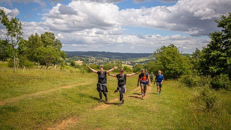 A group of hikers are trekking up a grassy hill in Shropshire.