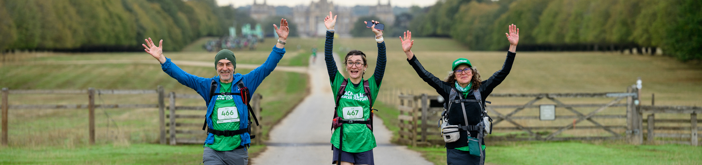 Three Mighty Hikers with their arms in the air and smiling as they walk.