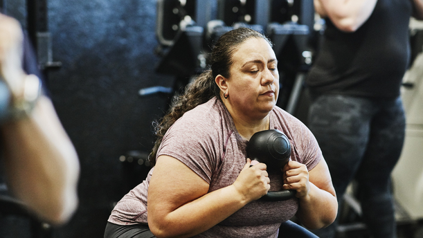 A person in a gym doing a kettlebell squat.