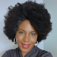 A brown lady with brown curly afro hair.