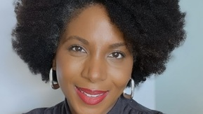 A brown lady with brown curly afro hair.