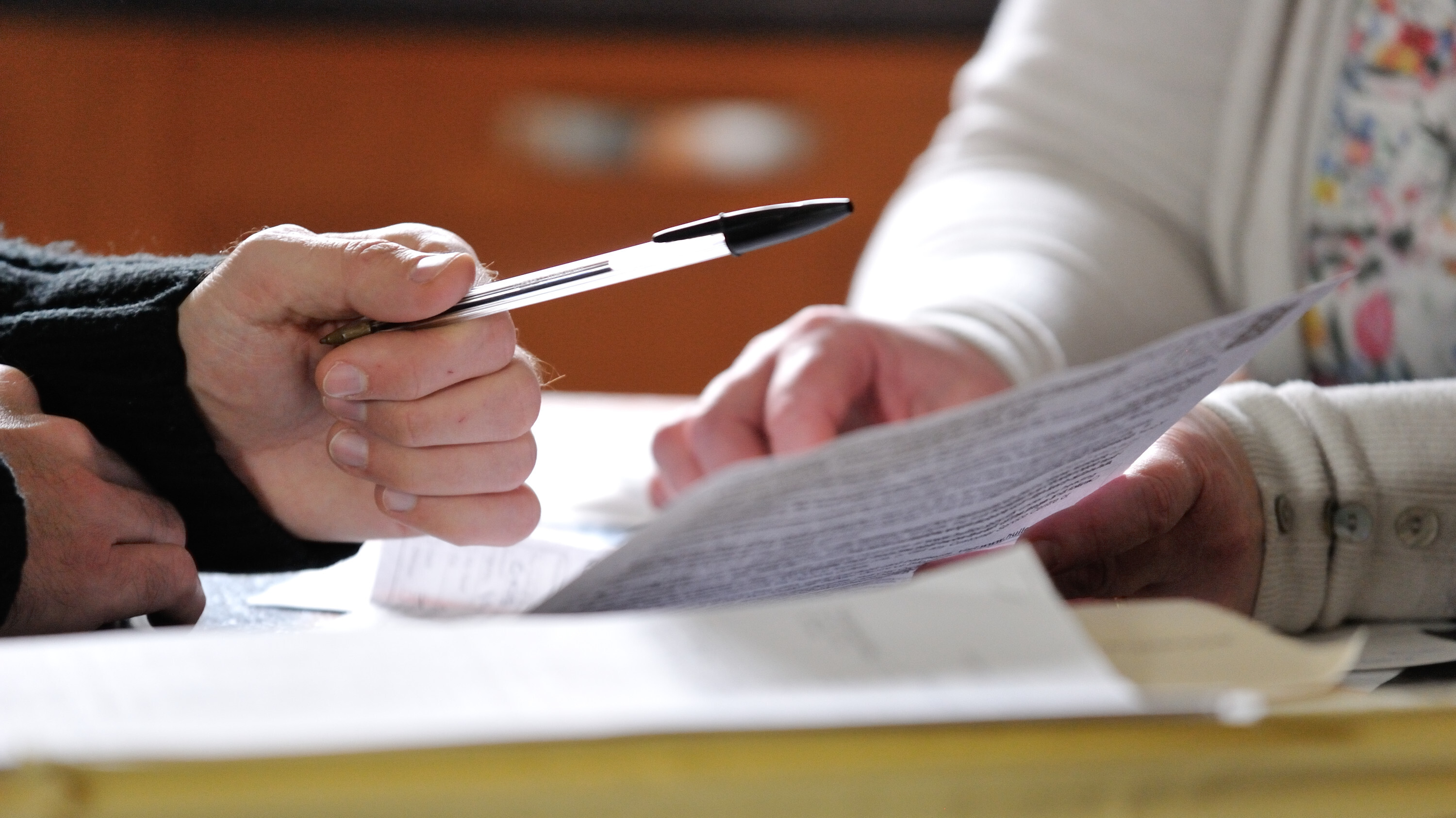 Two people's hands completing an application form