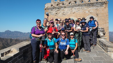 A large group of hikers standing together and posing for a photo on the Great Wall of China.