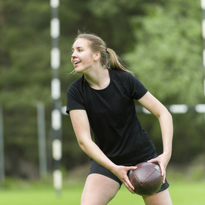 Girl wearing all black sportswear getting ready to pass a rugby ball.