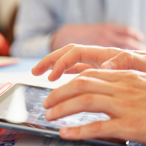 Close up image of a man's hands using an ipad.