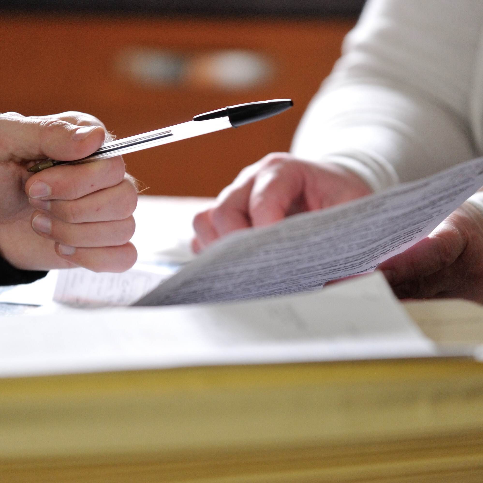 Two people's hands completing an application form