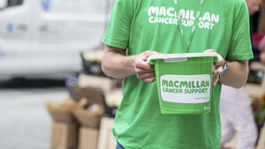A person wearing a Macmillan t-shirt holding a fundraising bucket