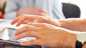 Close up image of a man's hands using an ipad.