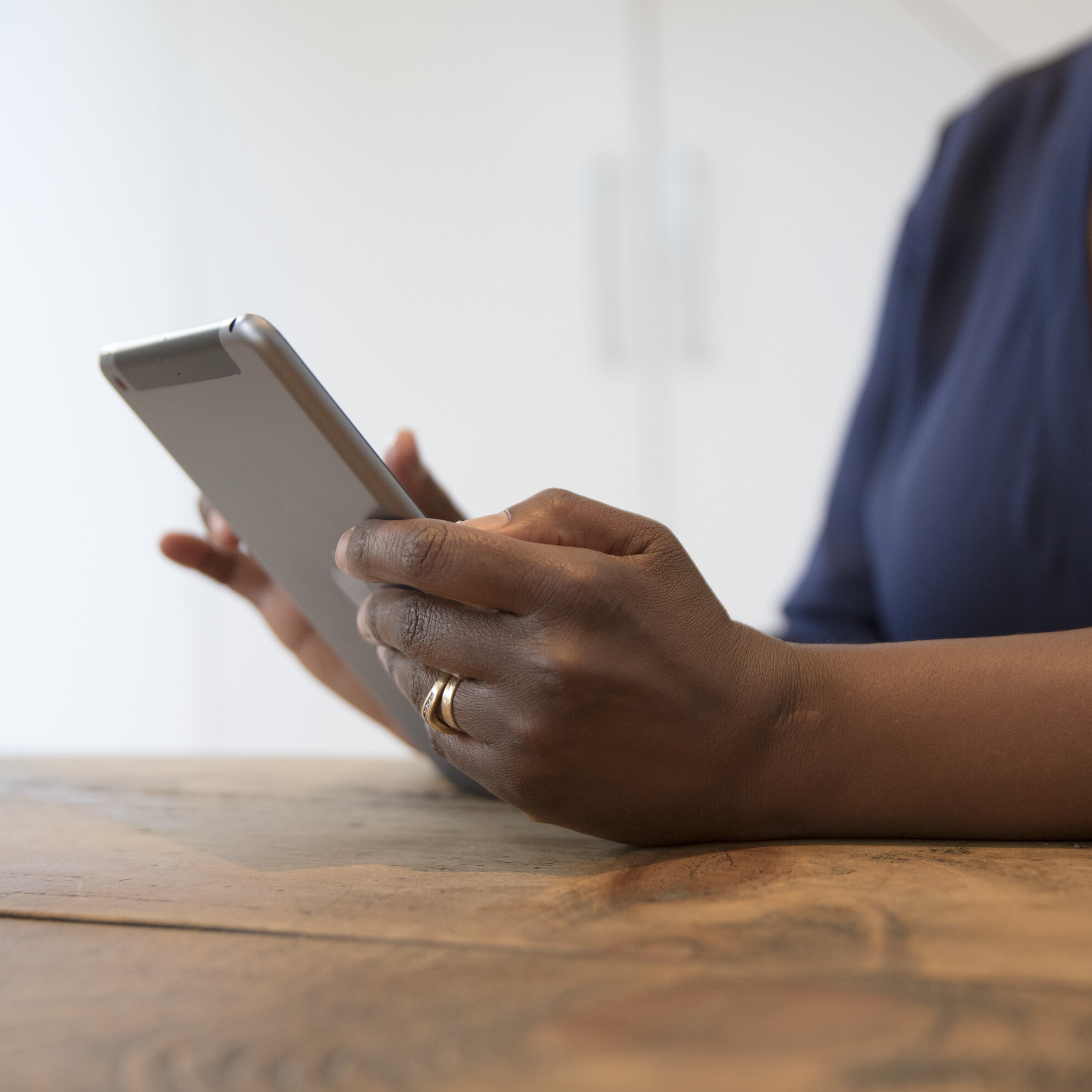 Close up of a woman holding a tablet and reading information online.