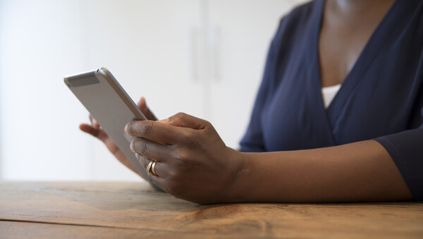 Close up of a woman holding a tablet and reading information online.