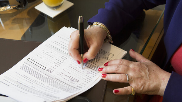 A close-up of a women's hands writing on an application form