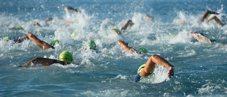 Group of open water swimmers swimming with green swimming caps on