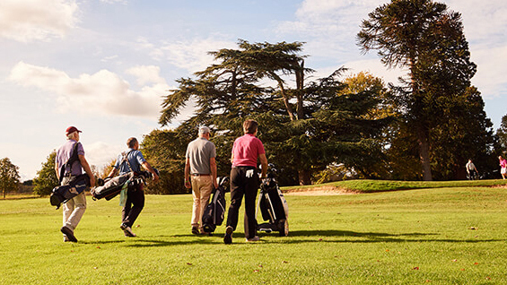 Four golfers walking along the fairway of a golf course