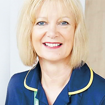 A portrait of a nurse, Catherine. She is white with blonde hair, is smiling and wearing a blue nurse uniform.