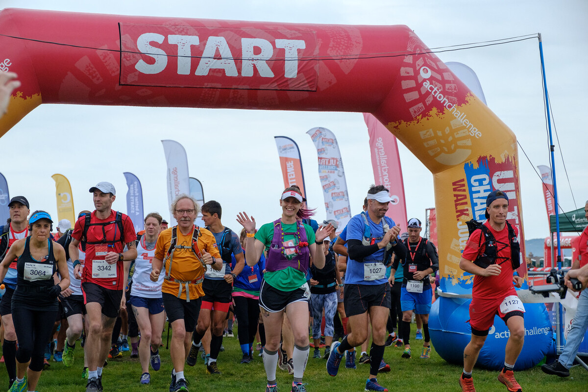 People jogging over the start line of the Ultra Challenge, most wearing running drinks vests.