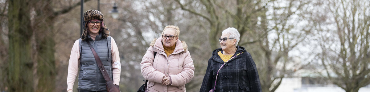 Three people walking together around a park.
