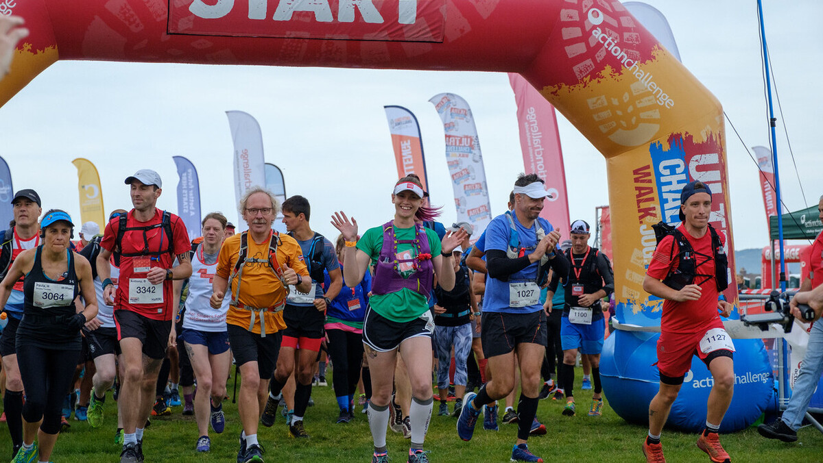 People jogging over the start line of the Ultra Challenge, most wearing running drinks vests.