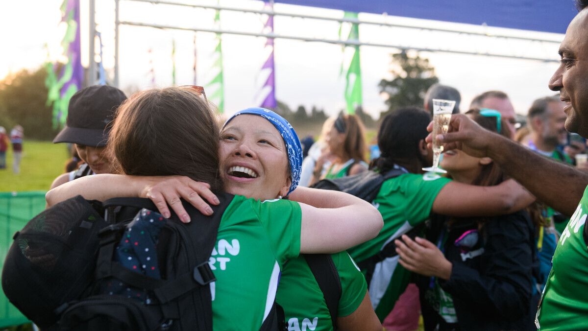Two women hugging at the finish line of an outdoor event.