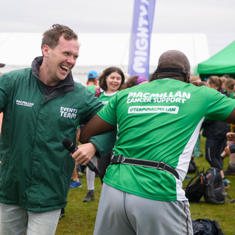 Two people dancing at the finish line of a Macmillan Mighty Hike event.