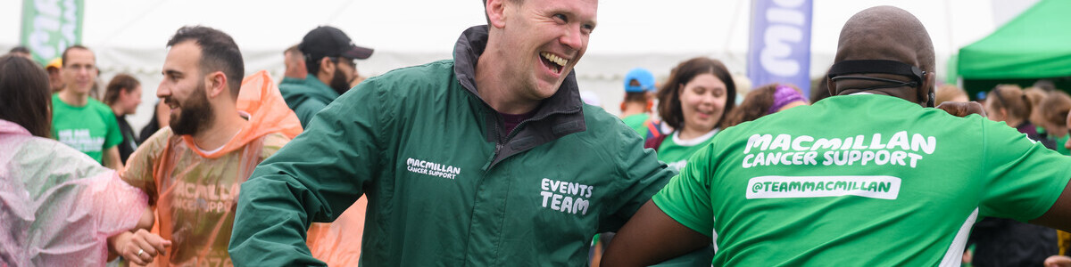 Two people dancing at the finish line of a Macmillan Mighty Hike event.