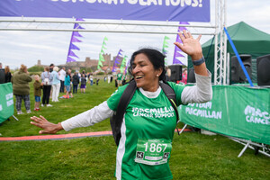 A woman celebrating as she crosses the finishing line at an outdoor event.