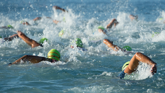 Group of open water swimmers swimming with green swimming caps on