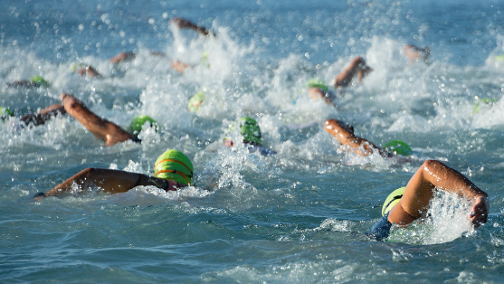 Group of open water swimmers swimming with green swimming caps on