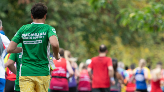 A group of runners photographed from behind   with someone wearing a green Macmillan running t-shirt in the foreground.