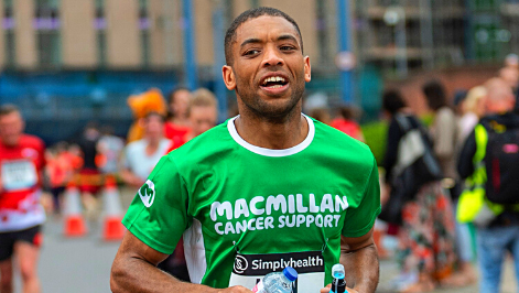 A man and a woman running next to each other wearing green Macmillan running t-shirts and smiling.