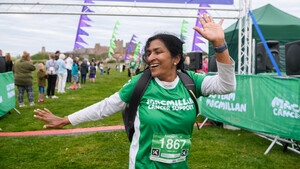 A woman celebrating as she crosses the finishing line at an outdoor event.