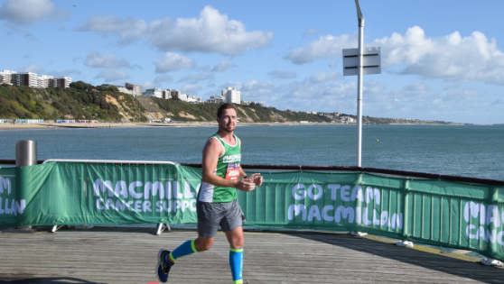 Man wearing a Macmillan running vest running on Bournemouth Pier.