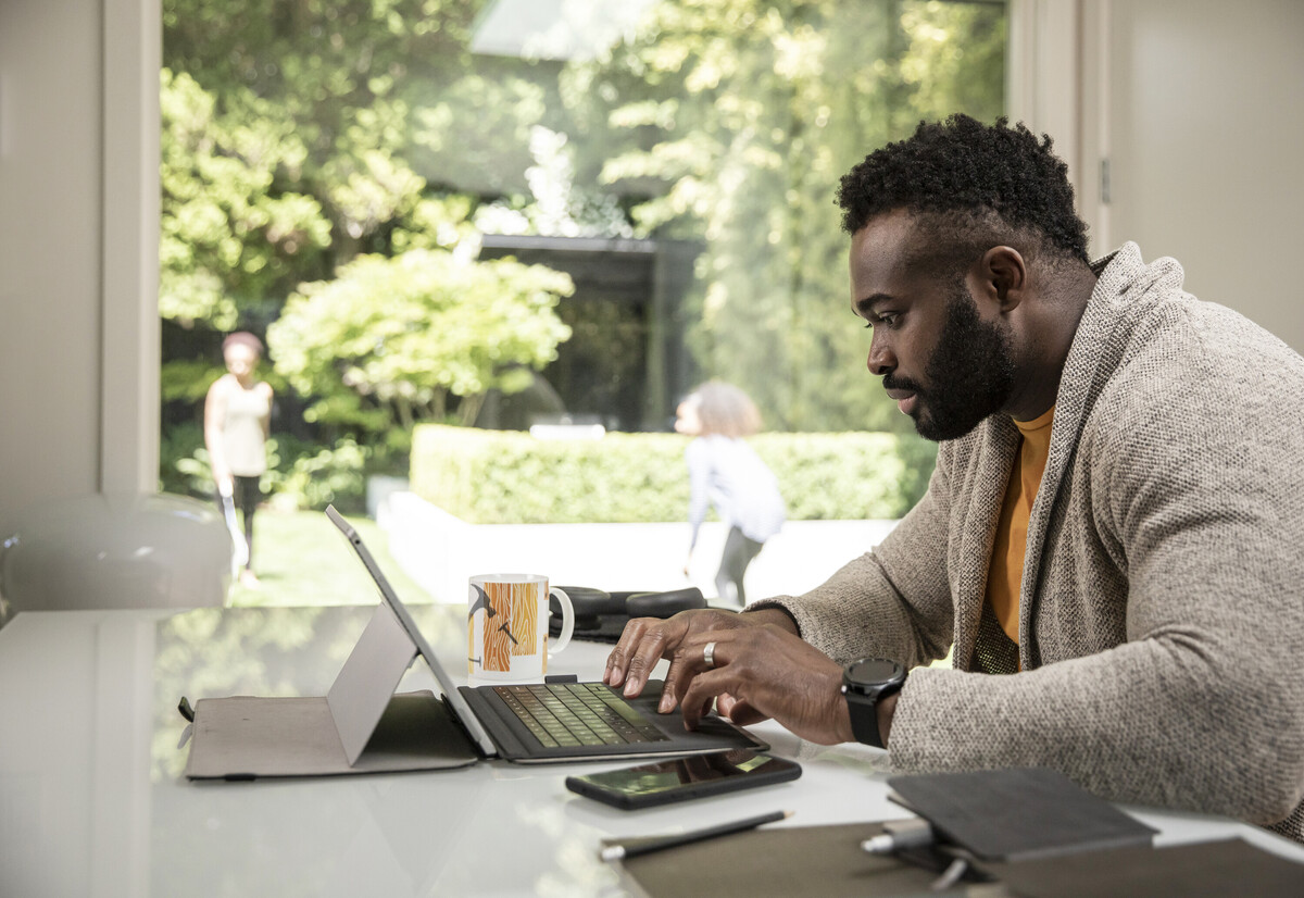 A side profile of a Black man on laptop.