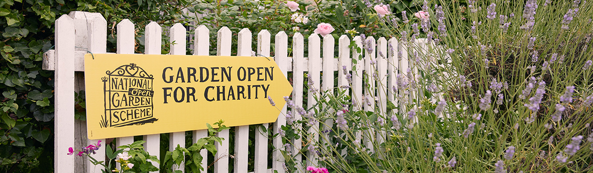 A garden fence with a sign that reads 'Garden open for charity'.