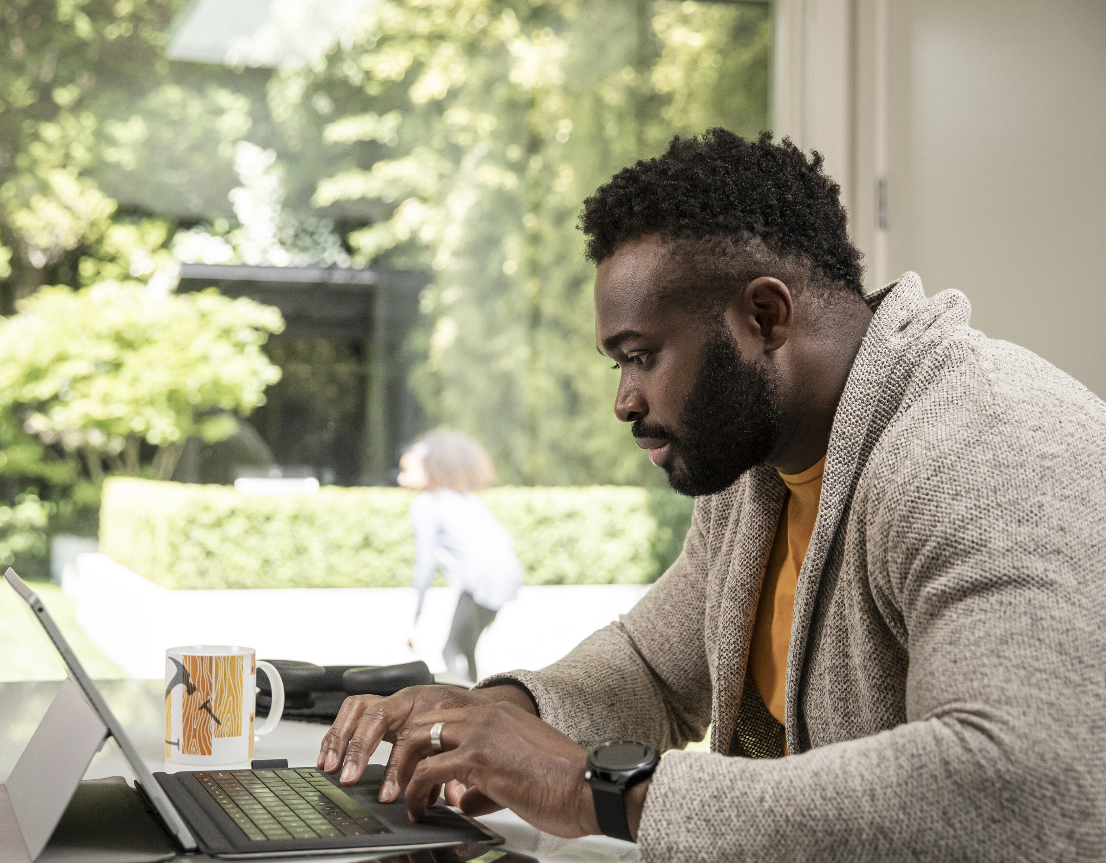 A side profile of a Black man on laptop.