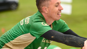 A man in a green top reaching out to grab something.