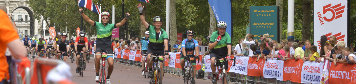 3 cyclists coming towards the finish line of the RideLondon event waving and clapping.