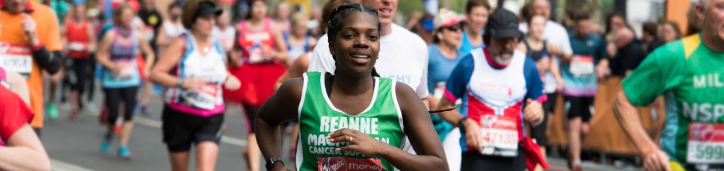 Image of lots of people running the London Marathon with Reanne in the middle of the picture wearing a Macmillan running top with her name on it and smiling to camera